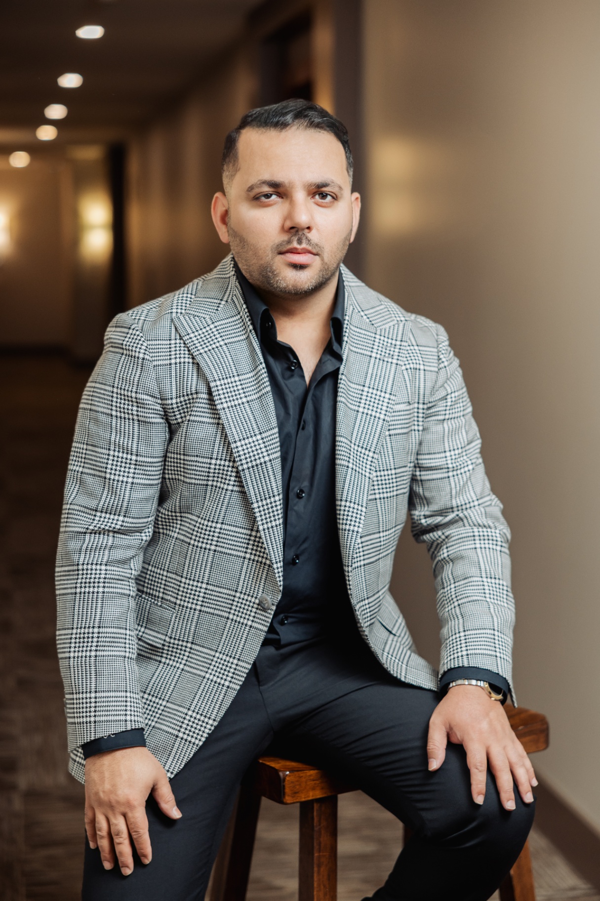 Rajat Nagpal in a bespoke Prince of Wales check jacket, seated on a stool